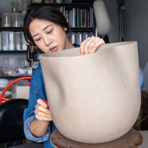 Portrait of Yueh Luo working on a ceramic piece